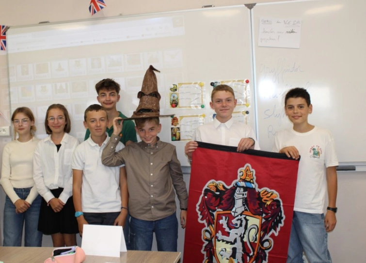 Groupe d'élèves en classe posant avec le Choixpeau magique et un blason Gryffondor