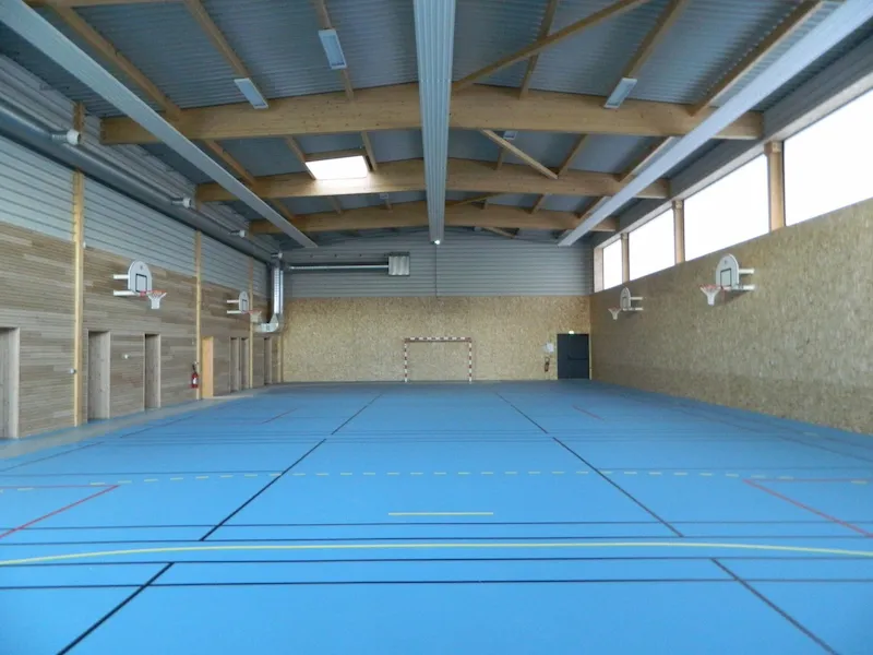 Le grand gymnase intérieur de l'école avec son revêtement de sol bleu.